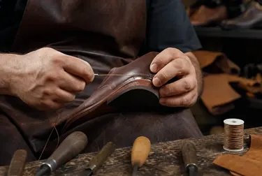Sapateiro utilizando máquina de costura para reparar calçado.